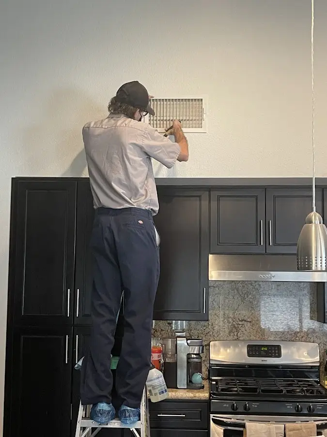 Technician inspecting an air vent during HVAC service in Teaneck